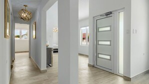 Ein moderner Flur mit Holzboden, weißen Wänden und einer Glastür mit sandgestrahlten Scheiben.