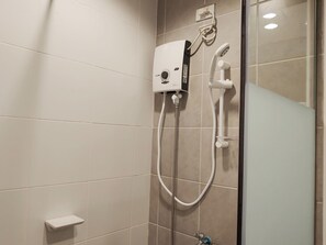 Un área de ducha con un cabezal de ducha de mano y un panel de control en la pared.
