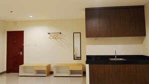 A modern kitchen with wooden cabinets, a black countertop, and a sink. There are two wooden cabinets below the countertop. - Kaizen Suites (Manila)