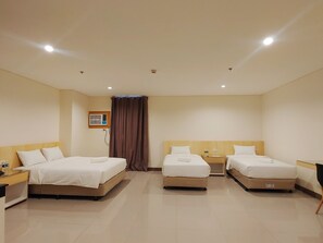 Habitación de hotel con dos camas individuales, una mesita, una silla y un aire acondicionado instalado en la pared.