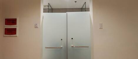 A double door with a handle and a metal bar, likely a bathroom or utility room door.