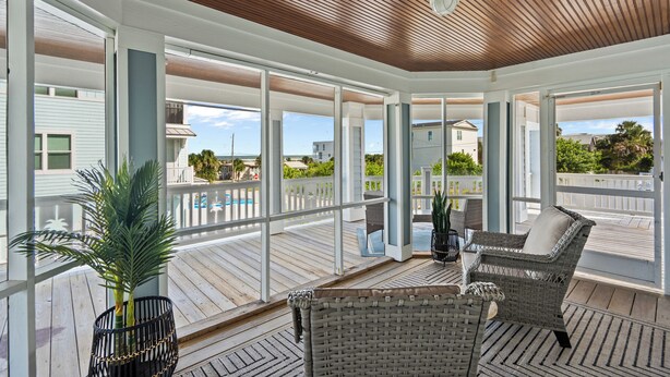 A covered outdoor area with wicker furniture and a potted plant.
