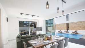 Een moderne eetruimte met uitzicht op het zwembad, een bank en een televisie.