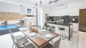 Een moderne keuken met een marmeren aanrecht, een eethoek met uitzicht op een zwembad en een stenen muur.