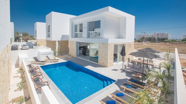 Een modern huis met twee verdiepingen, een zwembad, terras en uitzicht op zee.