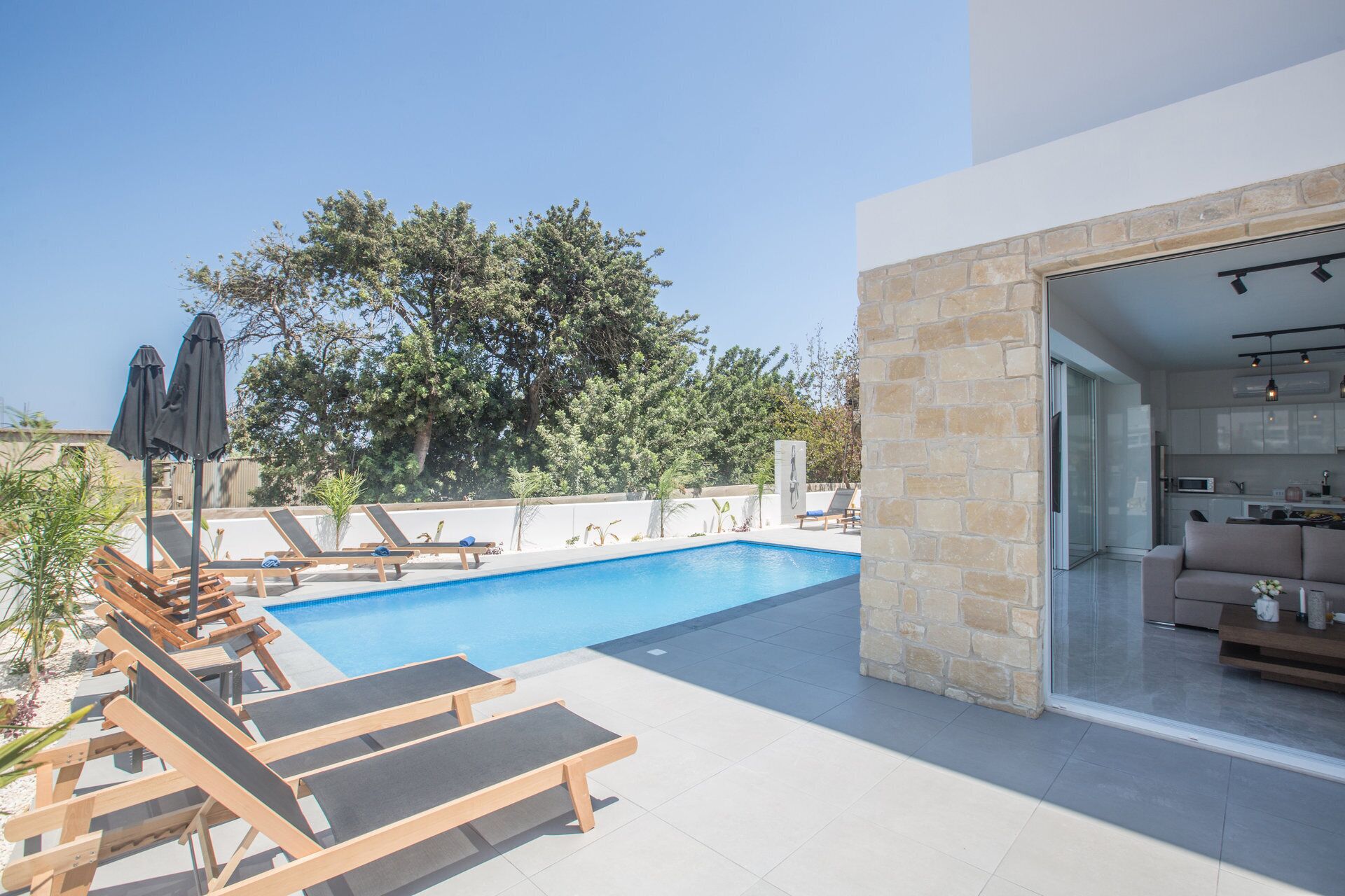 A modern outdoor pool area with lounge chairs and a clear view of the surrounding trees.