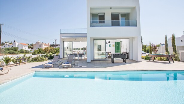 Une maison moderne à deux étages, avec une piscine en premier plan.