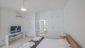 Une chambre d’hôtel moderne équipée d’un lit, d’un téléviseur posé sur un meuble, d’une armoire et d’un miroir.