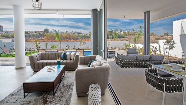 Ein geräumiger Wohnbereich mit großem Fenster und Blick auf Pool und Landschaft.