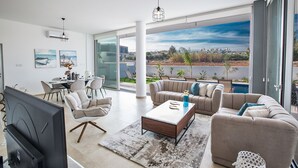 Ein modernes Wohnzimmer mit einem großen Schiebeglasfenster, das auf einen Balkon mit Blick auf die Stadt führt.
