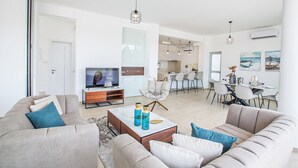 Ein geräumiges Wohnzimmer mit einer Sofagarnitur, einem Couchtisch mit dekorativen Flaschen und einem Fernseher.