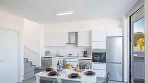 A modern kitchen with white cabinets, stainless steel appliances, and a dining area with a white table set for four. - The Ultimate 5 Star Holiday Villa in Protaras with Private Pool and Close to the Beach (Protaras)