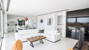Ett modernt vardagsrum med en vit soffa, ett träbord och orange fåtöljer.