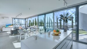 Een moderne keuken met een groot eiland, witte kasten en uitzicht op de omgeving.