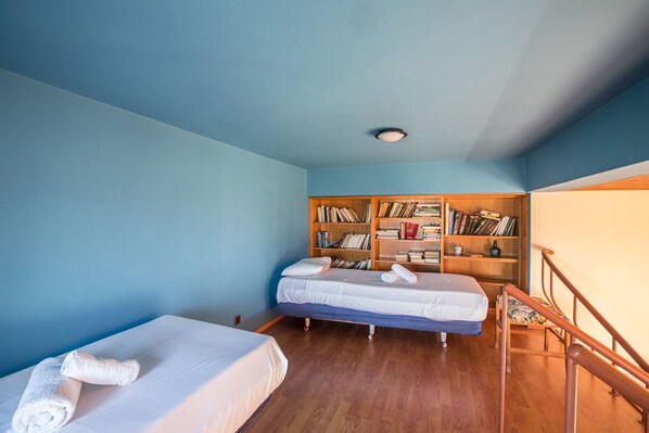 Una habitación con dos camas individuales, una estantería de madera y una escalera de madera.