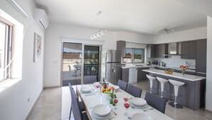 A modern kitchen with a dining area, featuring a large island, built-in appliances, and a view of the outdoors. - Amazing Villa on Protaras with Private Pool, Protaras Villa 1586 (Protaras)