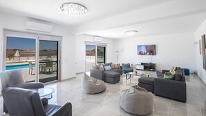 A modern living room with a pool view, grey sofas, and a flat-screen TV. - Amazing Villa on Protaras with Private Pool, Protaras Villa 1586 (Protaras)