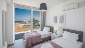 Une chambre d’hôtel avec deux lits, une grande fenêtre donnant sur la ville, un ventilateur de plafond et un appareil de climatisation.