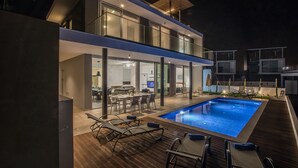Une maison moderne dotée d’une piscine, d’un espace extérieur aménagé et d’un intérieur bien éclairé.