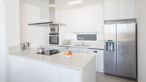 Une cuisine moderne avec des meubles blancs, des appareils en acier inoxydable et un îlot central.
