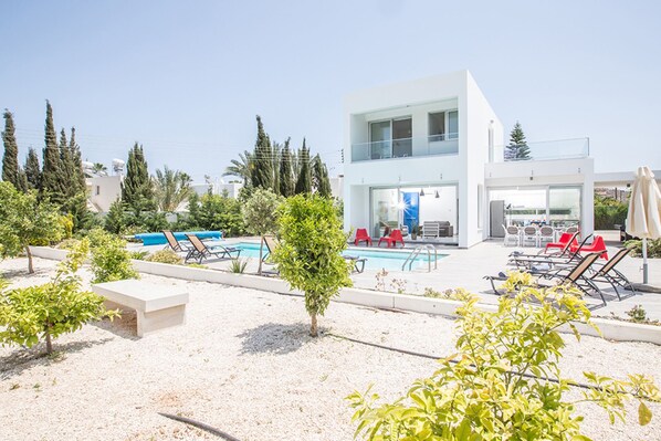 A modern hotel with a pool, outdoor seating, and a two-story building. - You will Love This Luxury 5 Bedroom Holiday Villa in Protaras with Private Pool, Protaras Villa 1550 (Protaras)