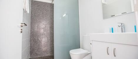 Un baño moderno con ducha, inodoro y tocador.
