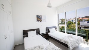 Une chambre d’hôtel moderne avec deux lits, une grande fenêtre donnant sur la ville et un design minimaliste.