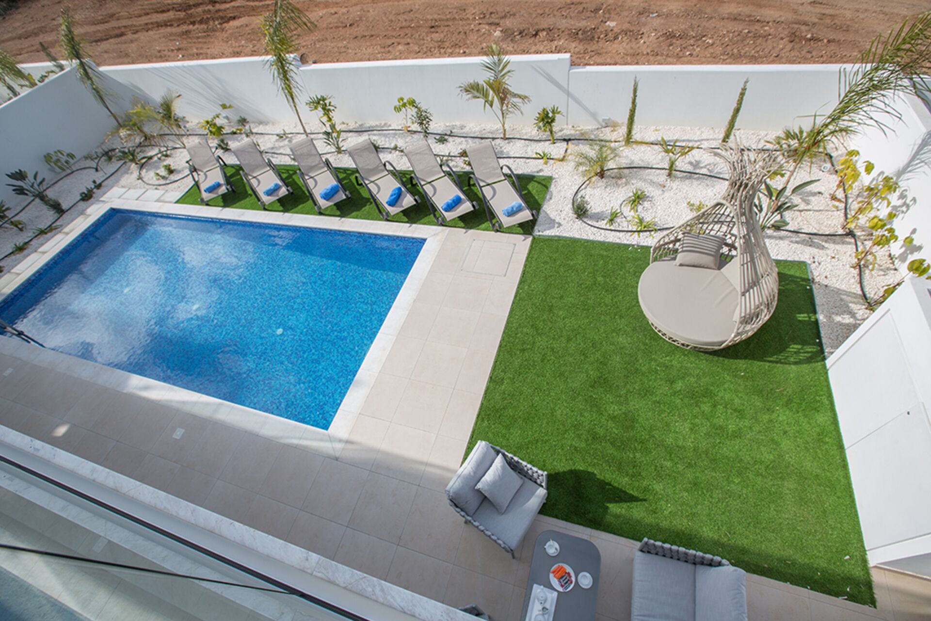 A swimming pool with adjacent lounge chairs and a small seating area with a table.