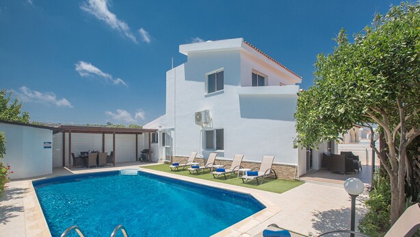 A modern poolside area with a clear blue pool, sun loungers, and a white building with multiple windows. - The Complete Guide to Renting Your Exclusive Holiday Villa in Protaras with Private Pool and Close to the Beach (Protaras)
