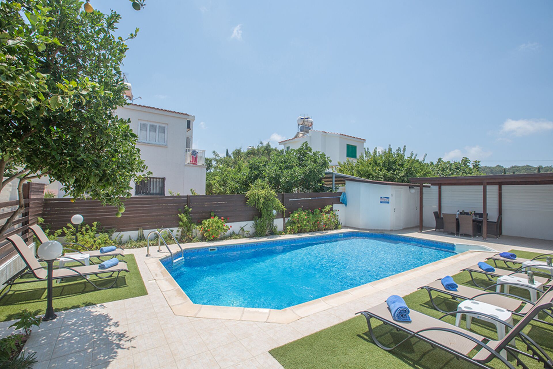 A swimming pool with lounge chairs and a small building in the background.