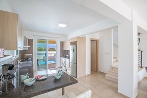 A modern kitchen with a granite countertop, stainless steel appliances, and a view to a balcony. - Rent Your Dream Protaras Holiday Villa and Look Forward to Relaxing Beside Your Private Pool (Paralimni)