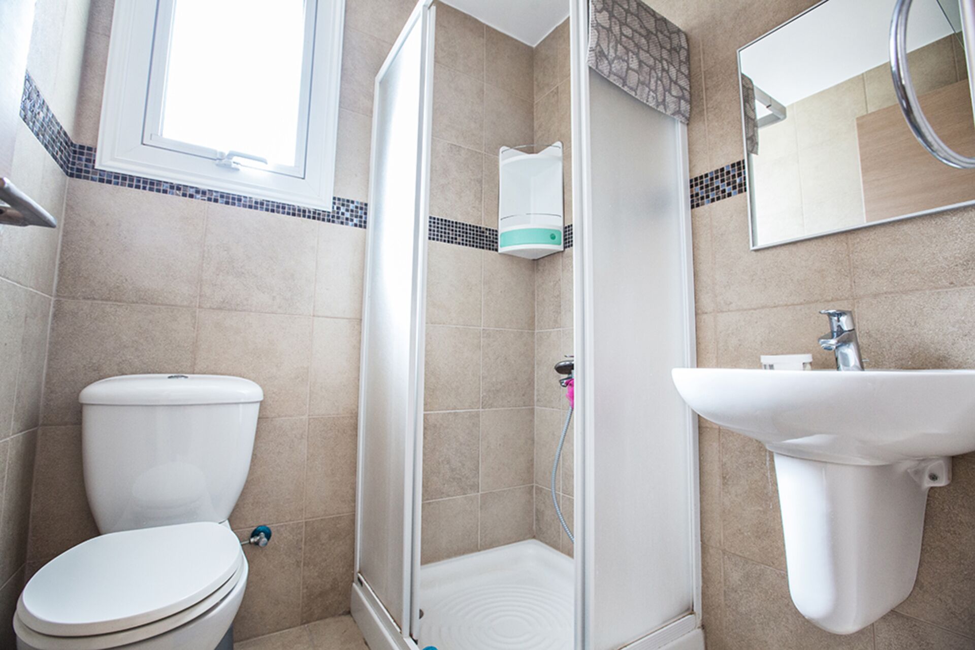 A bathroom with a toilet, a shower, and a sink.