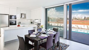 A modern kitchen with white cabinets and a dining area with a table set for four. - The Ultimate 5 Star Holiday Villa in Protaras with Private Pool and Close to the Beach (Protaras)