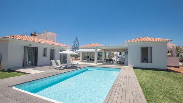 A modern pool area with a rectangular pool, lounge chairs, and a covered seating area.