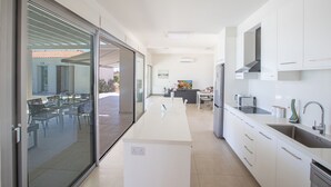 A modern kitchen with white cabinets, a built-in oven, and a large window overlooking a patio.