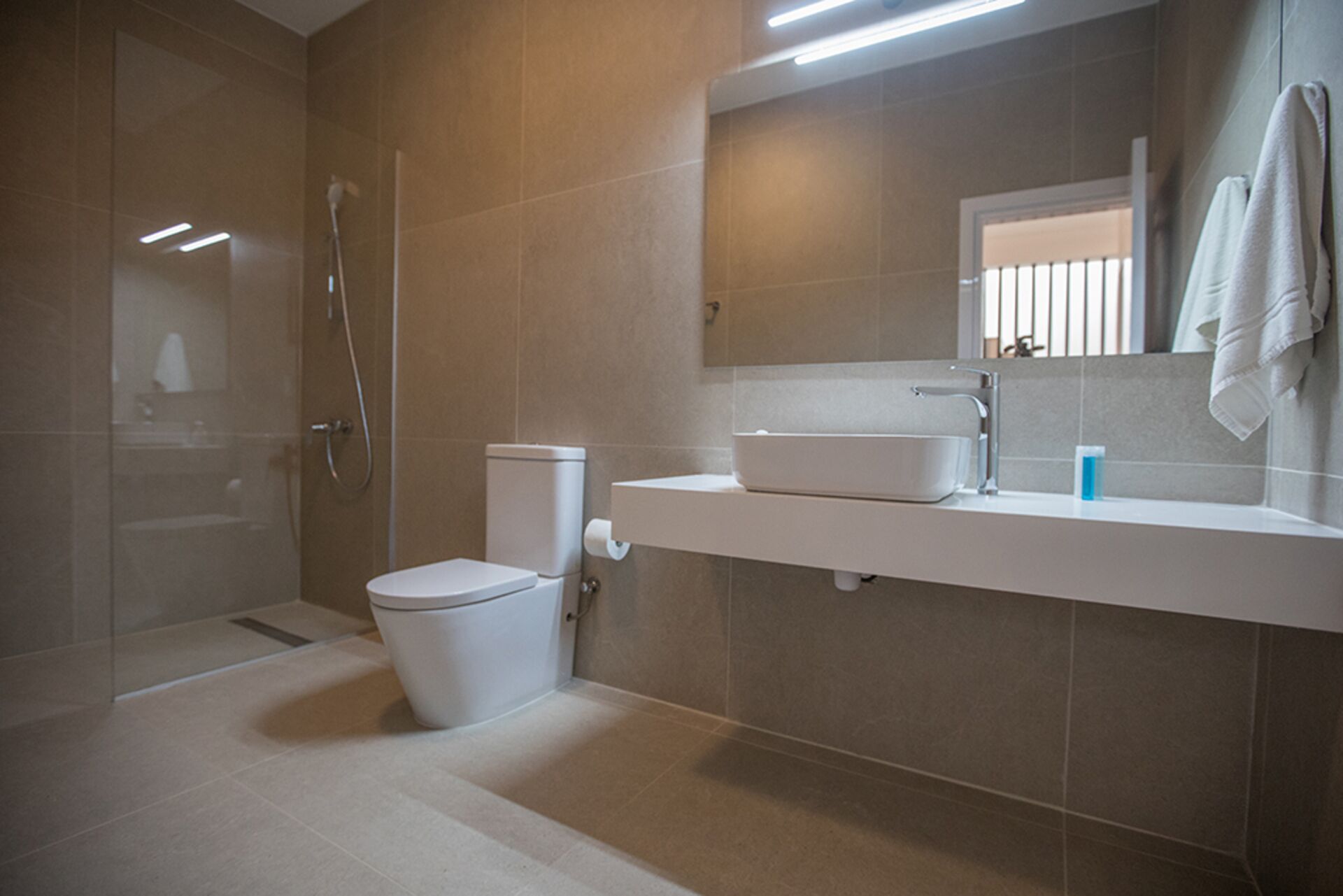 A modern bathroom with a toilet, sink, and shower.