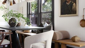 Un comedor con una mesa de madera, sillas, un banco y una planta en maceta.