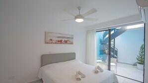 A bedroom with a bed, a ceiling fan, a painting, and a view of a balcony with a staircase. - The Complete Guide to Renting Your Exclusive Holiday Villa in Protaras with Private Pool and Close to the Beach (Protaras)