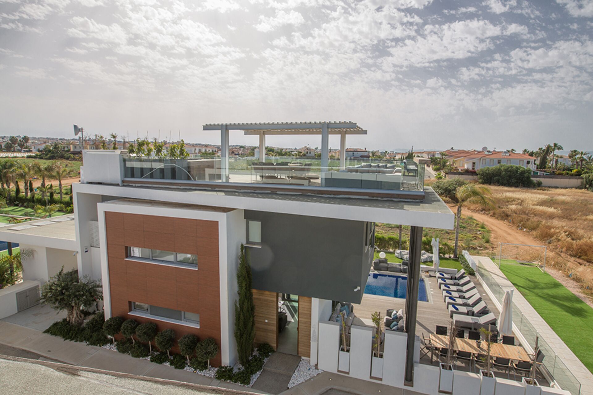 A modern house with a rooftop pool, a covered patio, and a view of the surrounding landscape.