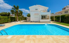 A modern house with a swimming pool, a covered patio, and a well-maintained garden.