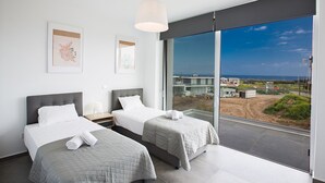 Ein modernes Hotelzimmer mit zwei Betten, einem großen Fenster und Blick auf die Stadt sowie Kunstwerken an der Wand.