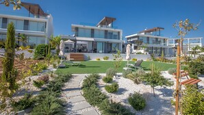 Ein modernes Resort mit mehreren Gebäuden, einer gepflegten Rasenfläche und verschiedenen Pflanzen.