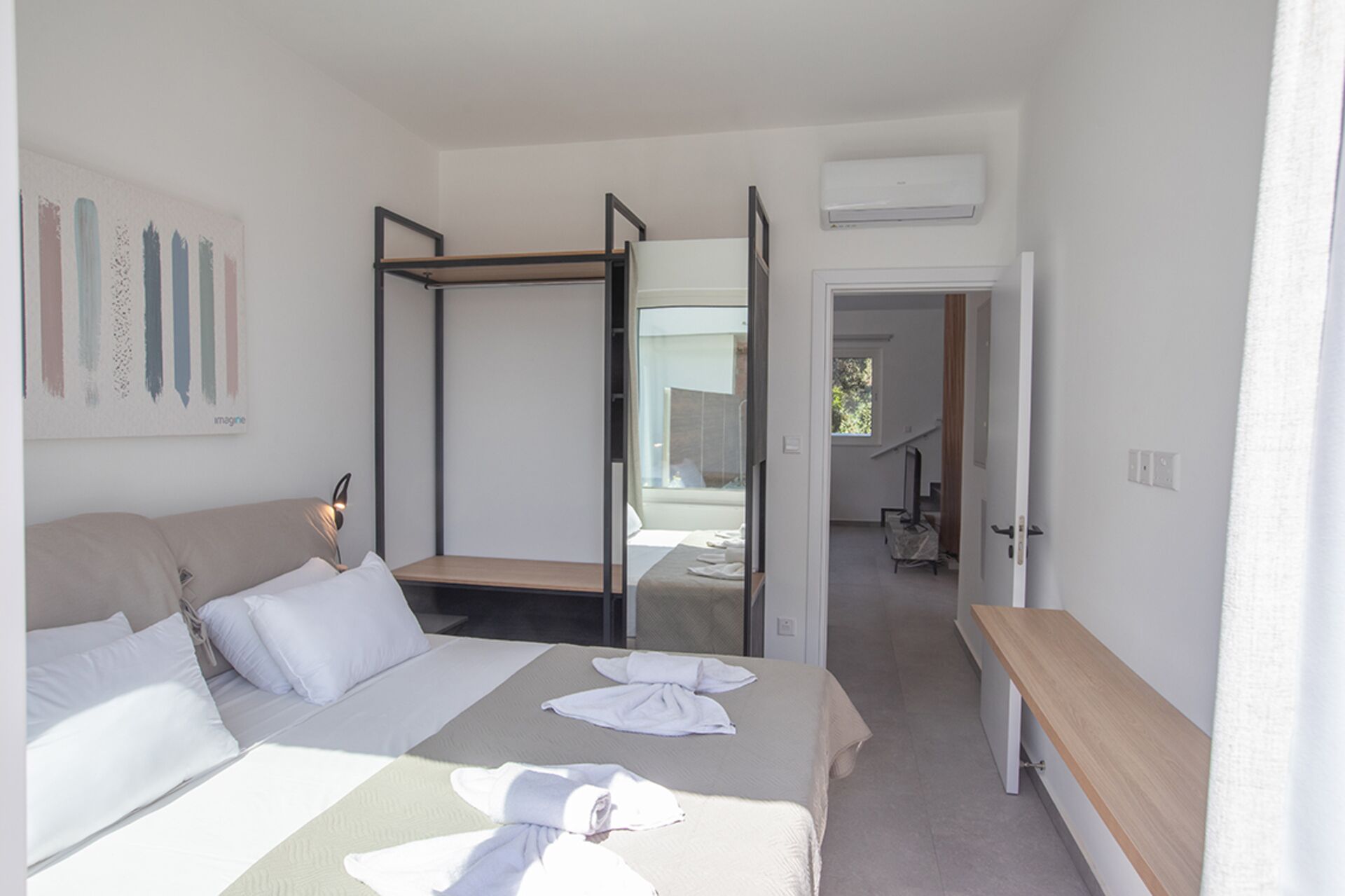 Een moderne hotelkamer met een bed, een bankje en uitzicht.