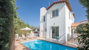 A two-story house with a swimming pool, outdoor seating, and a barbecue area.