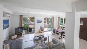 A modern living room with a sofa, TV, and dining area with a table and chairs.