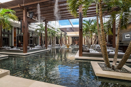 A spacious indoor pool area with seating and palm trees.
