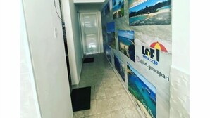 A hallway with a tiled floor, a door at the end, and a wall with multiple framed pictures. - Loft Vista Mar (Guarapari)