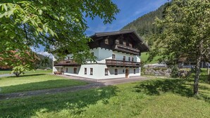 A traditional chalet-style building with a balcony, surrounded by lush greenery and mountains in the background. - Apartment 'Jägermeister' with Mountain View, Shared Garden and Wi-Fi (Sankt Martin bei Lofer)