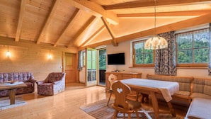 Un intérieur en bois comprenant une table à manger, des chaises, un canapé et un téléviseur fixé au mur.