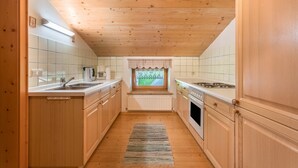 Une cuisine étroite avec des meubles en bois, une fenêtre donnant sur un beau paysage et un radiateur placé sous la fenêtre.